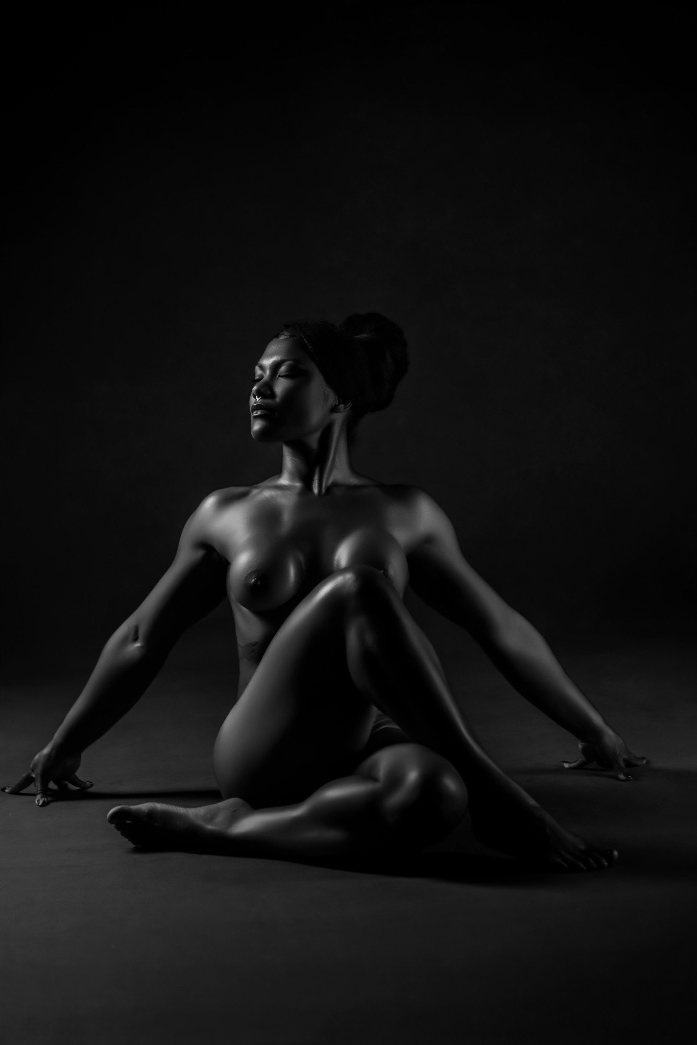 Sculptural black-and-white boudoir portrait seated against a dark background